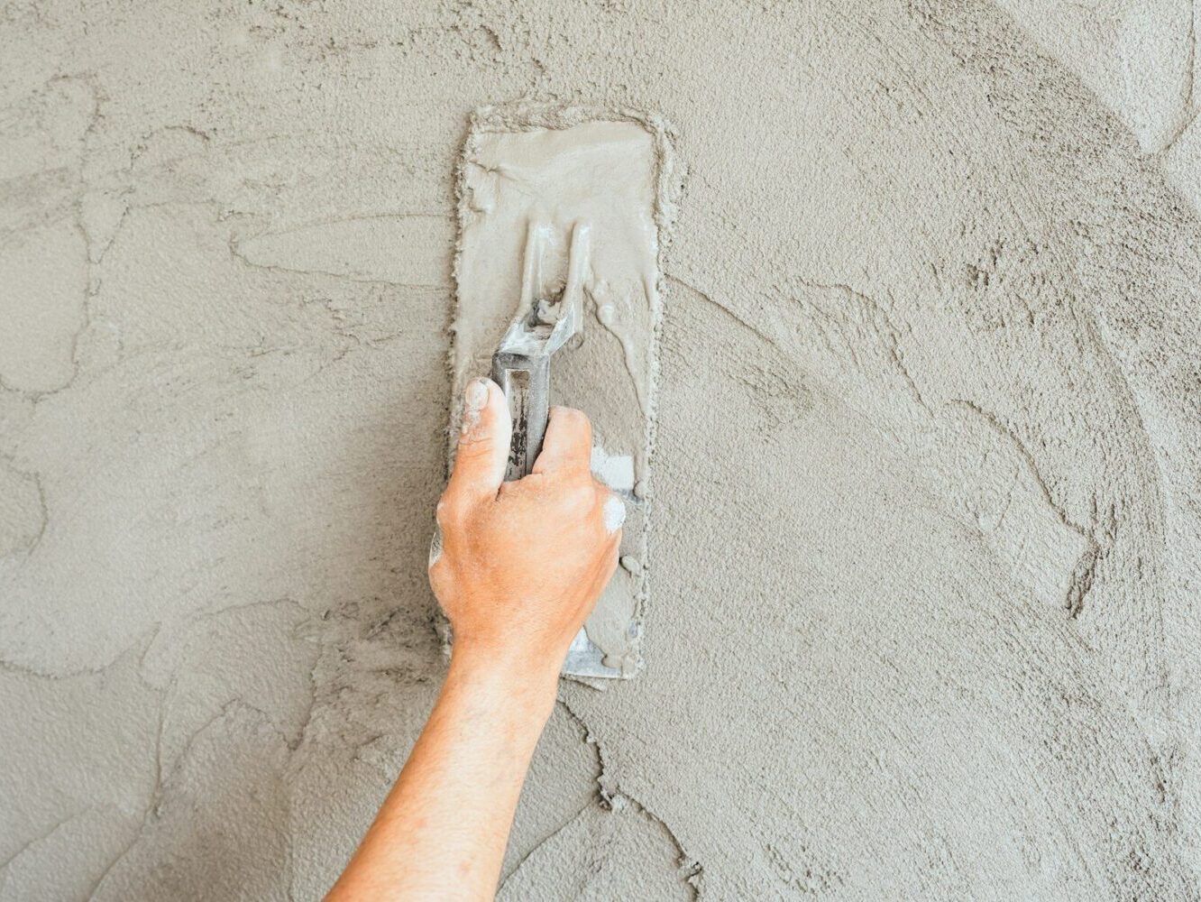 Hand plaster plastering with trowel handle wet grey cement wall background well free space for text